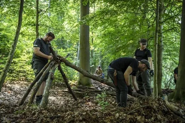 Personen bauen eine Struktur aus Ästen im Wald