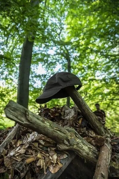Schwarze Mütze liegt auf einem Haufen aus Ästen und Blättern