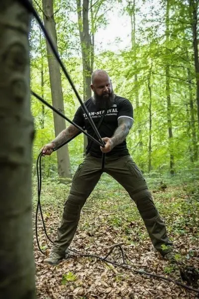 Seil wird mit beiden Händen gespannt, während der Boden mit Laub bedeckt ist