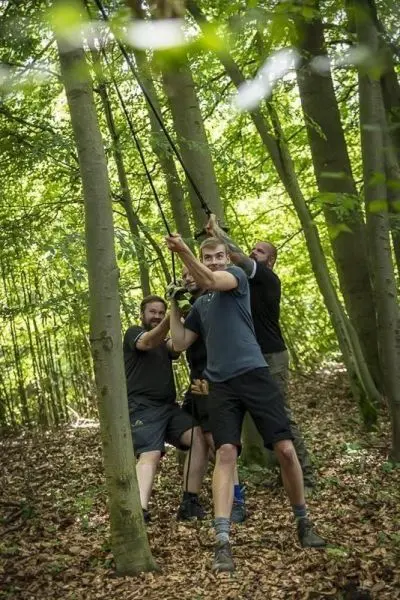 Seilbrücke wird von mehreren Personen zwischen Bäumen gespannt