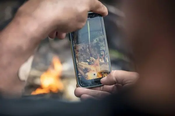 Smartphone zeigt Feuerstelle mit Holz und Zunder