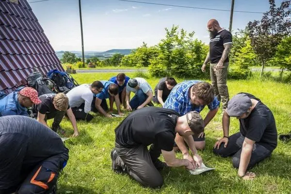 Teilnehmer analysieren Kartenmaterial auf einer Wiese