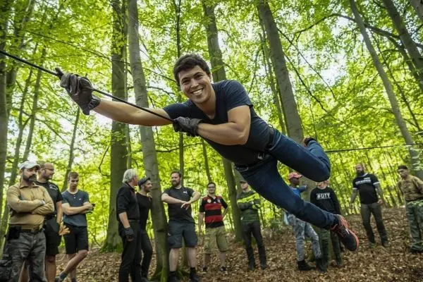 Teilnehmer schwingt an einer Seilbrücke zwischen Bäumen im Wald