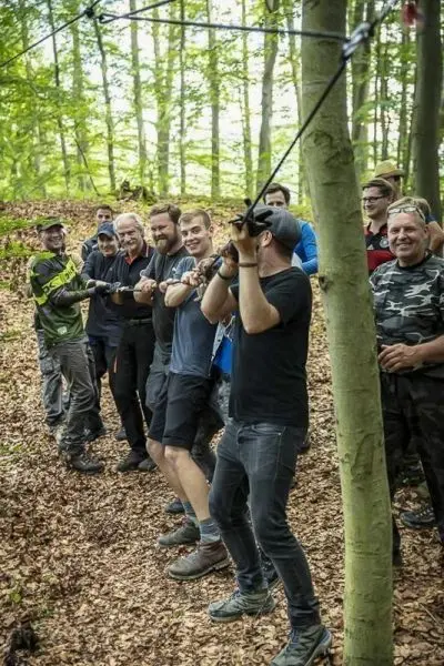 Teilnehmer ziehen an einem Seil, um eine selbstgebaute Seilbrücke zu testen