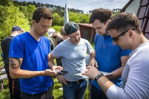 Vier Personen betrachten Karten und Smartphones im Freien