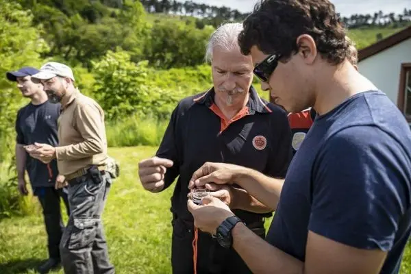 Zwei Personen betrachten gemeinsam einen Kompass, während andere im Hintergrund stehen