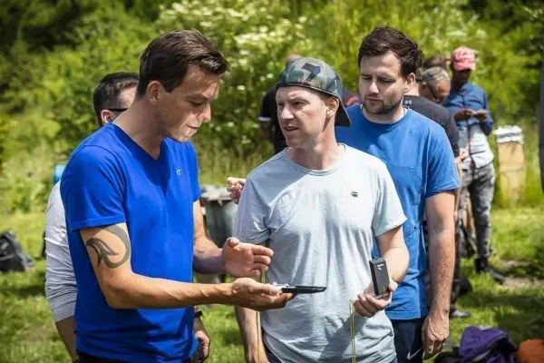 Zwei Personen diskutieren über ein Smartphone, während andere im Hintergrund warten