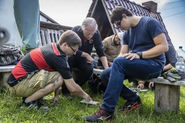 Zwei Personen untersuchen eine Karte auf dem Boden, während andere zuschauen