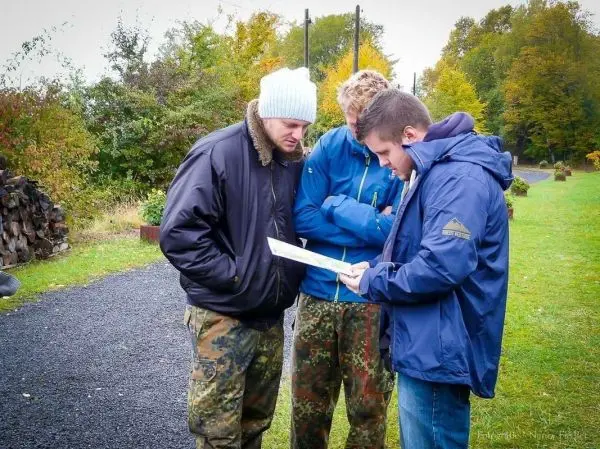 Drei Personen betrachten eine Karte auf einem Weg in der Natur