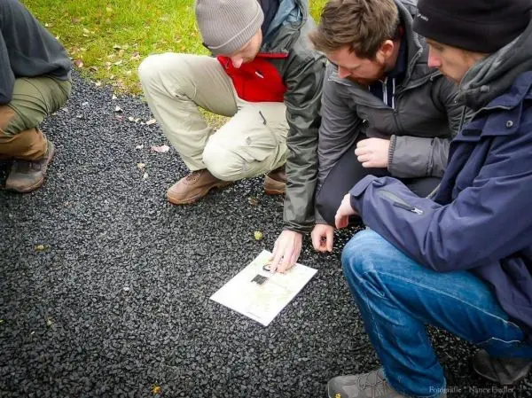 Drei Personen betrachten gemeinsam eine Karte auf dem Boden