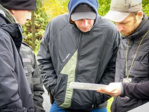 Drei Personen betrachten gemeinsam eine Karte im Freien