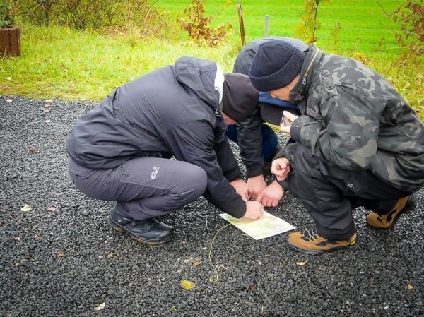 Drei Personen studieren eine Karte auf dem Boden
