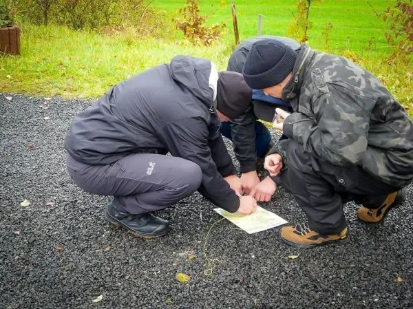 Drei Personen studieren eine Karte auf dem Boden