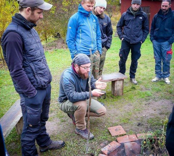 Ein Mann erklärt eine Feuertechnik vor einer Gruppe von Zuhörern