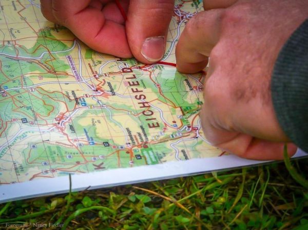 Finger zeigen auf eine topografische Karte mit markierten Wegen