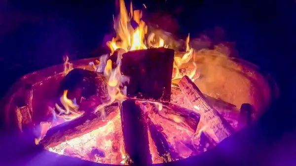 Flammen schlagen aus einem Lagerfeuer mit Holzscheiten im Feuerkreis