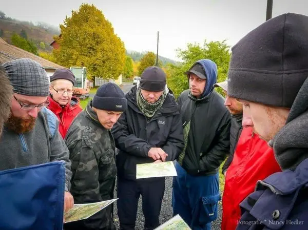 Gruppe betrachtet Karten und diskutiert Orientierungspunkte im Freien