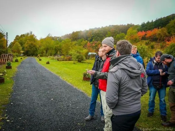 Gruppe steht auf einem Kiesweg und diskutiert in einer grünen Umgebung
