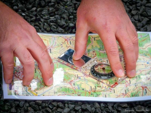 Hände legen einen Kompass auf eine Landkarte zur Orientierung