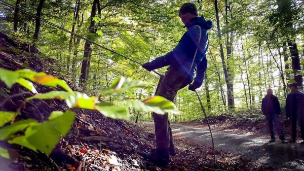 Junge spannt ein Seil an einem Hang zwischen Bäumen
