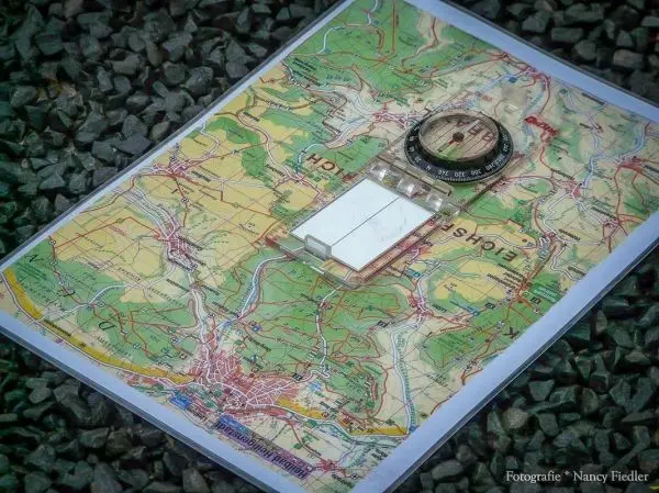 Karte mit Kompass auf Kiesuntergrund ausgelegt