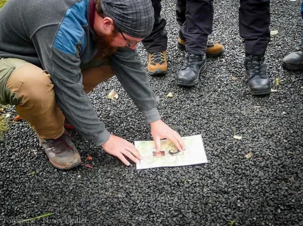 Karte wird auf dem Boden ausgebreitet und mit beiden Händen fixiert