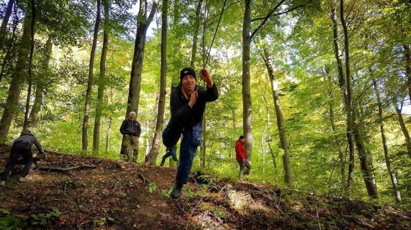 Mann demonstriert eine Technik im Wald, während andere Teilnehmer sich um ihn gruppieren