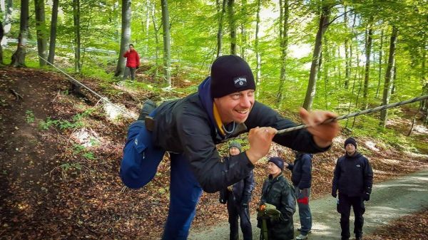 Mann schwingt an einer Seilbrücke zwischen Bäumen im Wald