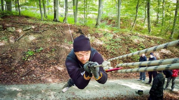 Mann schwingt an Seil über einen Hang im Wald