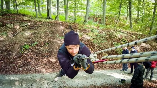 Mann schwingt an Seil über einen Hang im Wald