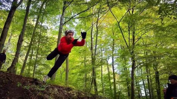 Mann springt von einem Hang in einem Waldgebiet