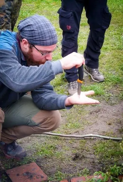 Messer wird vorsichtig auf die Handfläche eines Teilnehmers positioniert