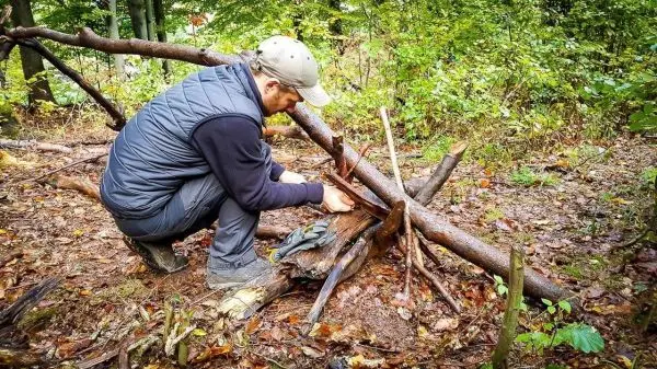 Person baut eine kleine Struktur aus Ästen im Wald