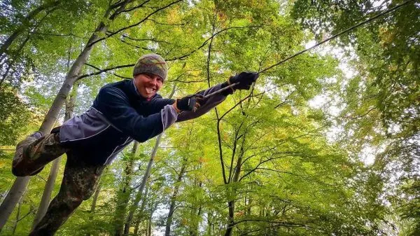 Person schwingt an einem Seil zwischen Bäumen im Wald
