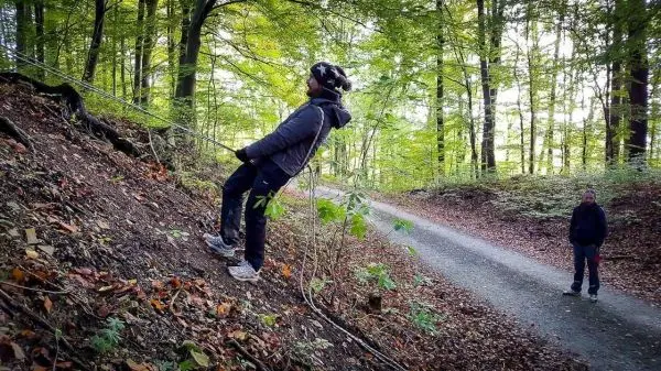 Person seilt an einem Hang im Wald ab