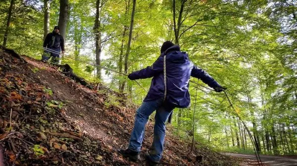 Person überquert selbstgebaute Seilbrücke im Wald