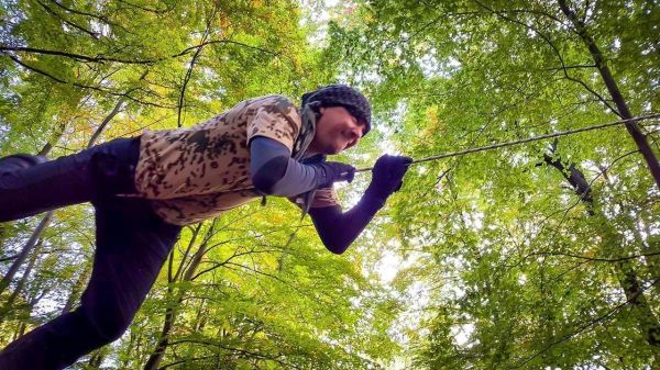 Person zieht an einer Schnur zwischen Bäumen im Wald