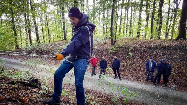 Seil wird von einer Person in der Natur gespannt, Zuschauer beobachten