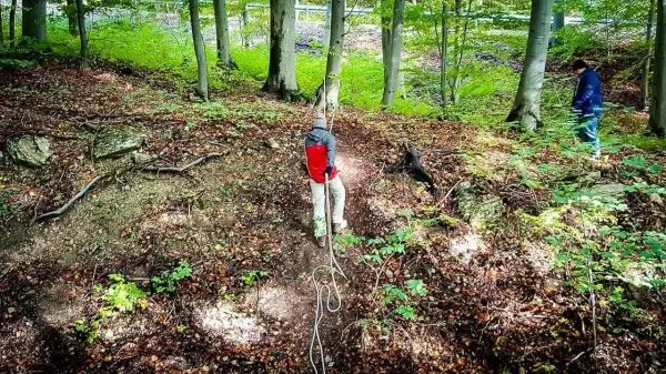 Seil wird zur Abseiltechnik an Baum befestigt, Person steht am Hang