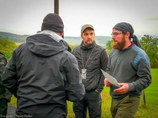 Vier Personen diskutieren im Freien, einer hält ein Blatt Papier in der Hand