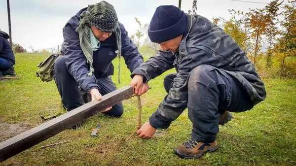 Zwei Personen bauen eine Konstruktion aus Holz und Seil