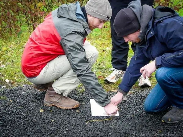 Zwei Personen knien auf Kies und betrachten eine Karte auf Papier