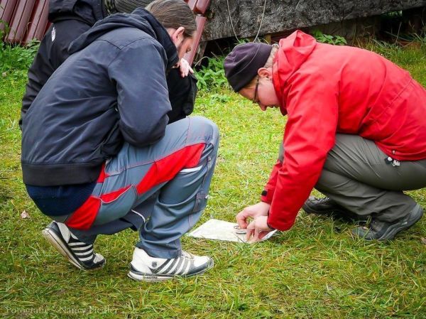 Zwei Personen studieren eine Karte auf dem Boden im Freien