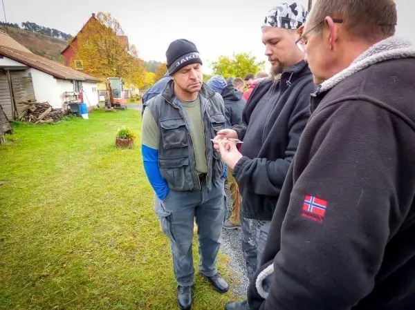 Drei Personen betrachten gemeinsam ein kleines Objekt im Freien