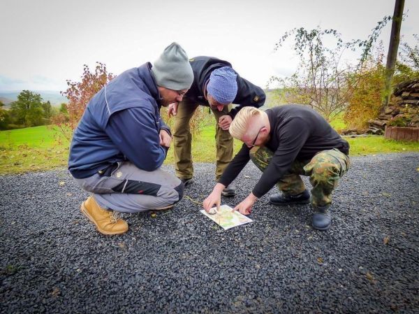 Drei Personen betrachten gemeinsam eine Karte auf dem Boden
