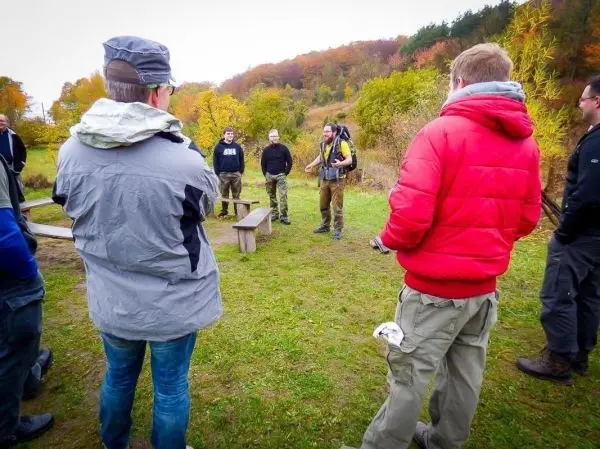 Ein Ausbilder erklärt Techniken im Freien, Teilnehmer hören aufmerksam zu
