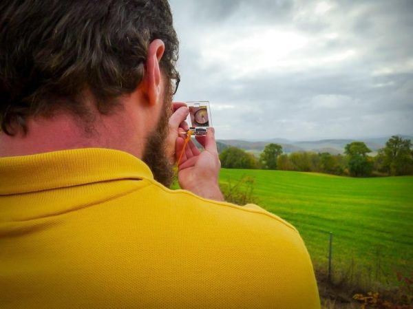 Ein Kompass wird auf eine Landschaft mit Wiesen und Hügeln ausgerichtet