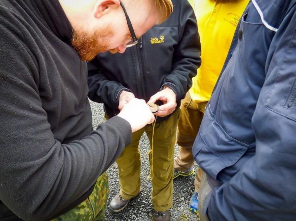 Ein Teilnehmer justiert eine Kompassnadel in einer Gruppe