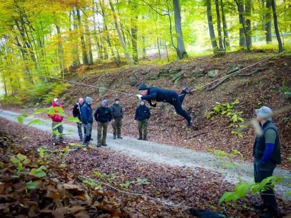 Ein Teilnehmer schwingt an einer Seilbrücke über einen Waldweg