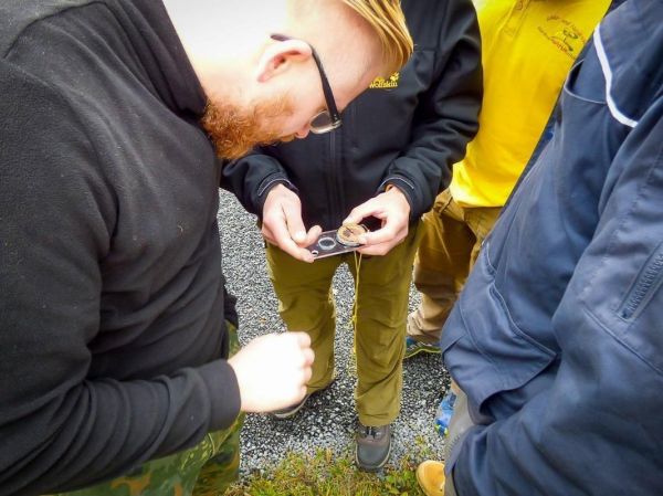 Eine Gruppe betrachtet gemeinsam eine Kompassnadel auf einem Tisch